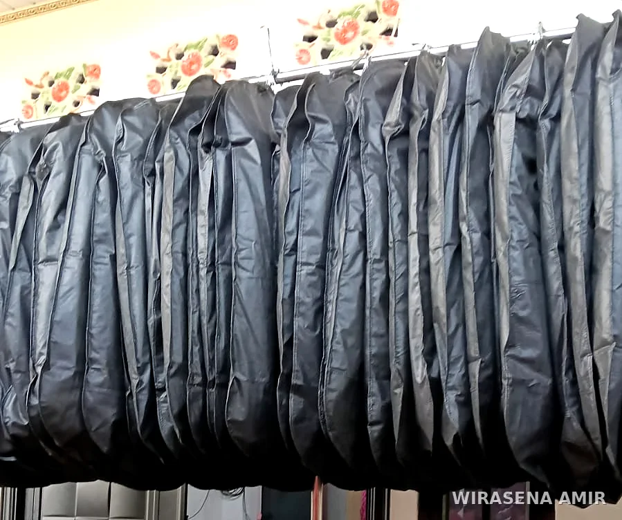 Puluhan jas dalam penutup pakaian hitam tergantung rapi di rak